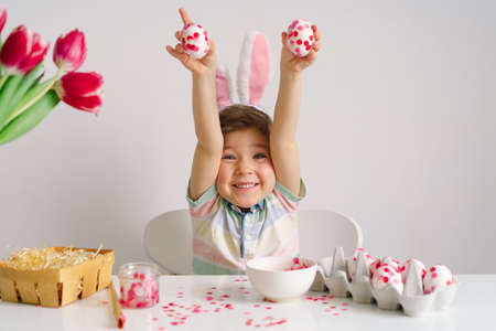 A little boy in bunny ears decorates Easter eggs. Easter concept. Spring seasonの写真素材