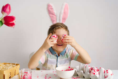 A little boy in bunny ears decorates Easter eggs. Easter concept. Spring seasonの写真素材