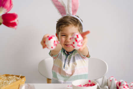 A little boy in bunny ears decorates Easter eggs. Easter concept. Spring seasonの写真素材