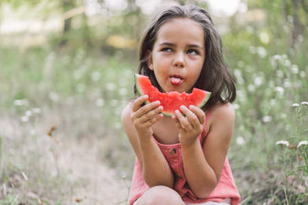 The girl is eating a watermelon. Childhood Summer mood.の写真素材
