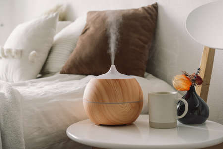 Aromatherapy Concept. Aroma oil diffuser on chair against in the bedroom. Air freshener. Ultrasonic...