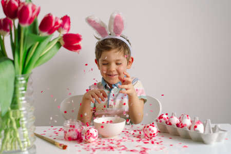 A little boy in bunny ears decorates Easter eggs. Easter concept. Spring season