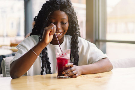 African woman with afro hair is drinking a cocktail.の写真素材