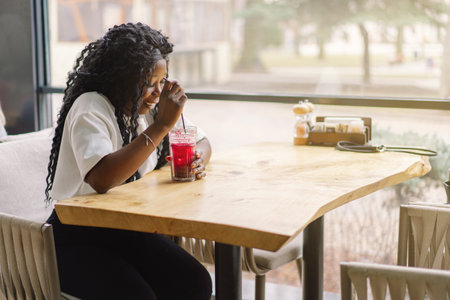 African woman with afro hair is drinking a cocktail.の写真素材