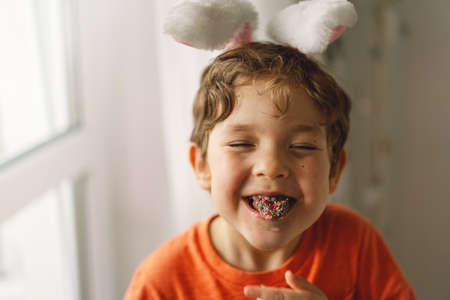 Cute boy eats and plays with Easter sprinkles.の写真素材
