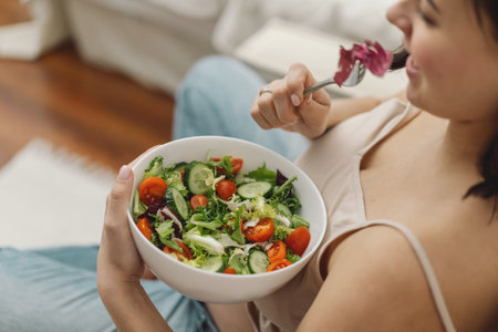 Pregnancy and healthy organic nutrition. Pregnant woman enjoying fresh vegetable salad.の写真素材
