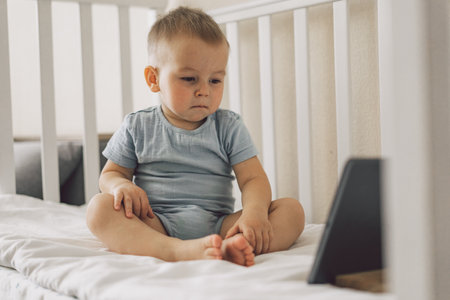 Little Boy sitting with a tablet in the room. The boy watching cartoons on the tablet. Technology...