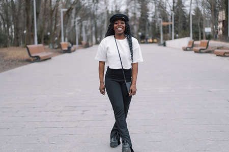 Photo portrait of cheerful black skinned girl. Afro girl walking in city park. Lifestyle