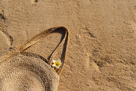 Straw bag on sand. Summer beach background. Summer time. Holiday by the sea. Vacation by the ocean background.の写真素材