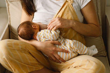 Newborn baby boy sucking milk from mothers breast. Portrait of mom and breastfeeding baby. Concept...