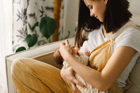 Newborn baby boy sucking milk from mothers breast. Portrait of mom and breastfeeding baby. Concept of healthy and natural baby breastfeeding nutrition.の写真素材