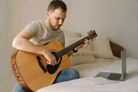 Man plays an acoustic guitar in an online lesson. Hobby a musician. life at homeの写真素材