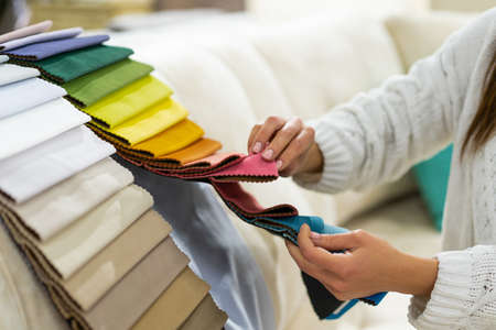The woman chooses the fabric on the sofa. Textile industry background. Tissue catalogの写真素材