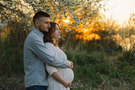 Young beautiful couple hugging in the spring garden. Concept pregnancy