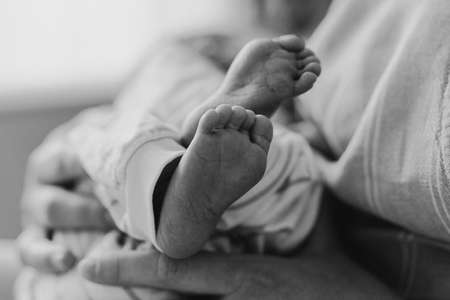 Black and white photo. Newborn baby boy sucking milk from mothers breast. Portrait of mom and breastfeeding baby. Concept of healthy and natural baby breastfeeding nutrition.の写真素材