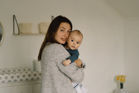 A young mother is play with little baby boy. Mother of a nursing baby. Happy motherhood. The family...