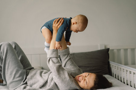 A young mother is play with little baby boy. Mother of a nursing baby. Happy motherhood. The family...