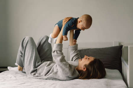 A young mother is play with little baby boy. Mother of a nursing baby. Happy motherhood. The family is at home. Portrait of a happy mother and child.の写真素材