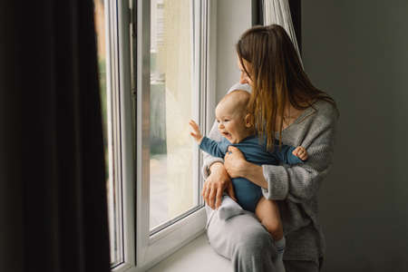 Mother playing with baby son at home near the window.の写真素材