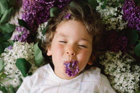 Portrait of a happy boy in lilac flowers. Happy childhood. Spring timeの写真素材