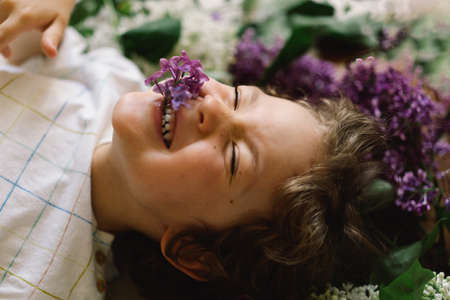 Portrait of a happy boy in lilac flowers. Happy childhood. Spring timeの写真素材