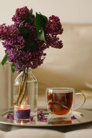 Still life details in home interior of living room. Lilac and cup of tea with candles.の写真素材