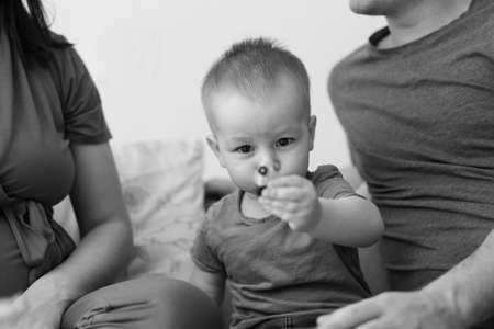 Black and white photo. Parents and Little Son, Having Fun Together At Home In Bed Room. Family life is about fun.の写真素材