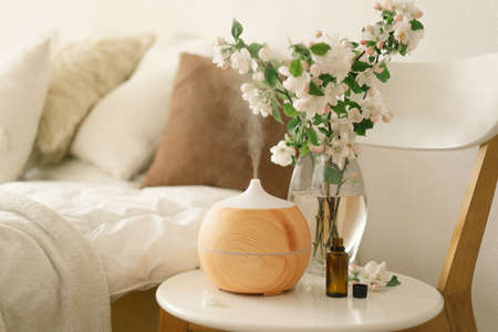 Aromatherapy Concept. Aroma oil diffuser on chair against in the bedroom. Air freshener. Ultrasonic aroma diffuser for homeの写真素材