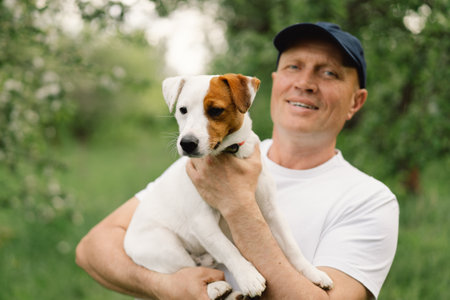 Man and dog friendship. Man play Jack Russell Terrier dogs in meadow. Man and Jack Russell Terrier dogs in nature. Beautiful dog.の写真素材