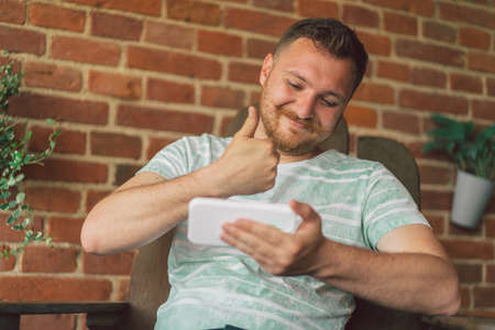 Young man laughs and talking by video call on the phone.の写真素材