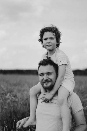 Happy fathers day. Little boy and father are playing in a beautiful field of red poppies.の写真素材