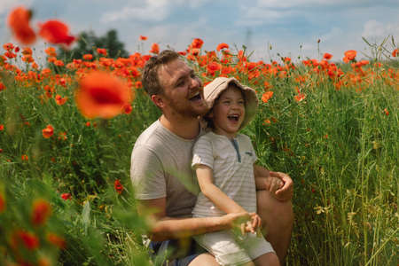 Happy fathers day. Little boy and father are playing in a beautiful field of red poppies.