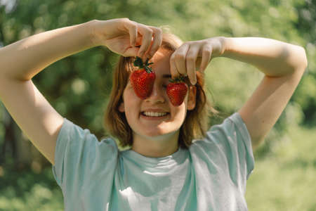 Young Teenager Girl with strawberry in a t-shirt in a outdoor and looking at camera. People and lifestyle conceptの写真素材