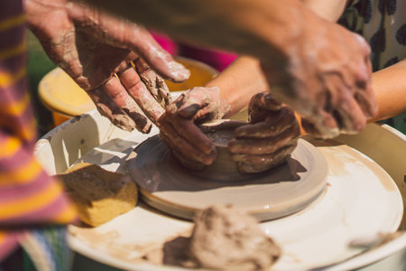 Potter making a clay object on pottery wheel in outdoors. Craftsman moulding clay with hands on pottery wheelの写真素材