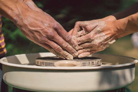 Potter making a clay object on pottery wheel in outdoors. Craftsman moulding clay with hands on pottery wheelの写真素材