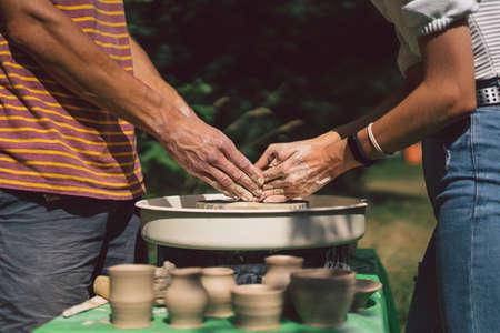 Potter making a clay object on pottery wheel in outdoors. Craftsman moulding clay with hands on...