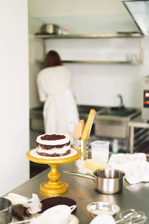 Confectioner girl is preparing a cake biscuit with white cream and chocolate. Cooking cakes.の写真素材
