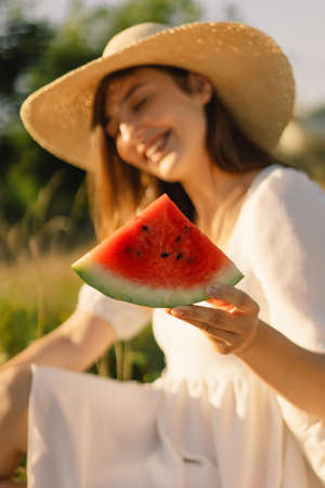 Happy girl in outdoor park with refreshing watermelon fruit. Woman eats a piece of watermelonの写真素材