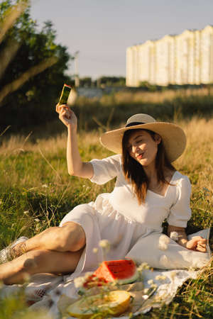 Happy girl in outdoor park with refreshing watermelon fruit. Woman eats a piece of watermelonの写真素材