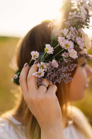 Summer lifestyle portrait of beautiful young woman in a wreath of wild flowers. Wreath on his headの写真素材