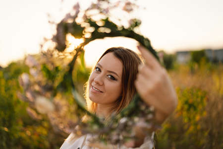 Summer lifestyle portrait of beautiful young woman in a wreath of wild flowers. Wreath on his headの写真素材