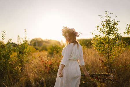 Portrait of a pregnant woman. A beautiful young pregnant woman in a white dress walks in the field.の写真素材