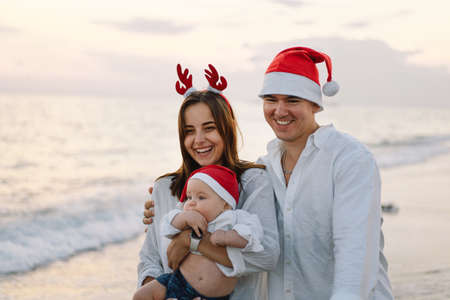 Family in a red Santa hat walk on the beach. Family celebrate Christmas and new year at tropics.