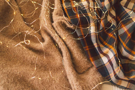 Background with warm sweaters and gerland. Knitted clothes. Space for text. Autumn conceptの写真素材