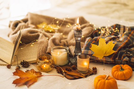 Sweaters and candles with autumn decor and book. Read, Rest. Still life details in home interior.の写真素材