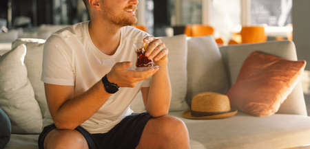 A man with mustache drinks and enjoy Turkish traditional hot tea in the lobby of a Turkish hotel