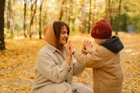 Mother and son are walking in the autumn forest. Autumn outdoor activity for family with kidsの写真素材