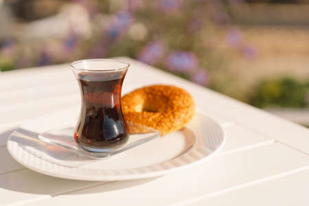 Crispy Turkish traditional bagel, simit with sesame and glass of turkish black tea