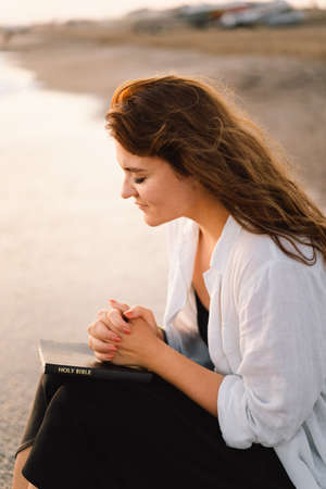 Woman closed her eyes, praying on a sea during beautiful sunset.の写真素材