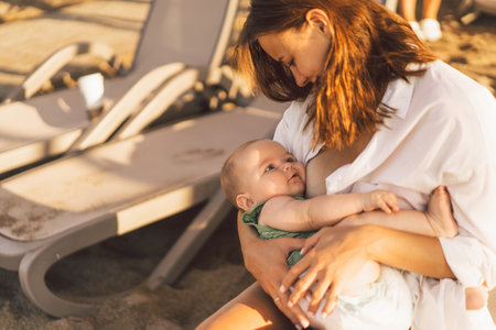 Newborn baby boy sucking milk from mothers breast on the beach.の写真素材